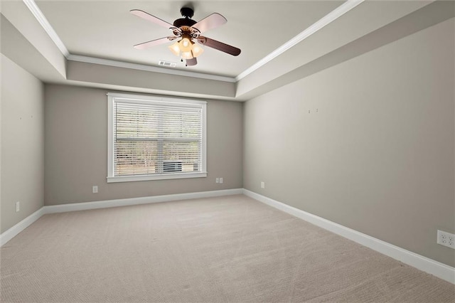 spare room featuring crown molding, a tray ceiling, light colored carpet, baseboards, and a ceiling fan