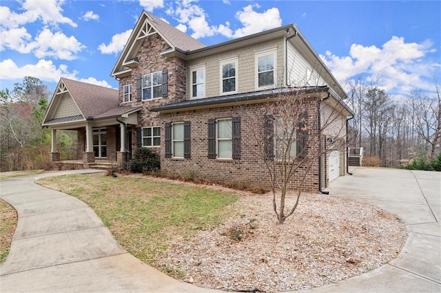 craftsman-style home with concrete driveway, a porch, brick siding, and a front yard