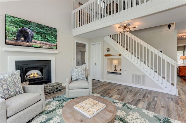125 Wolfscratch Dr, Big Canoe, GA 30143 - living room featuring stairs, wood finished floors, a warm lit fireplace, and a towering ceiling