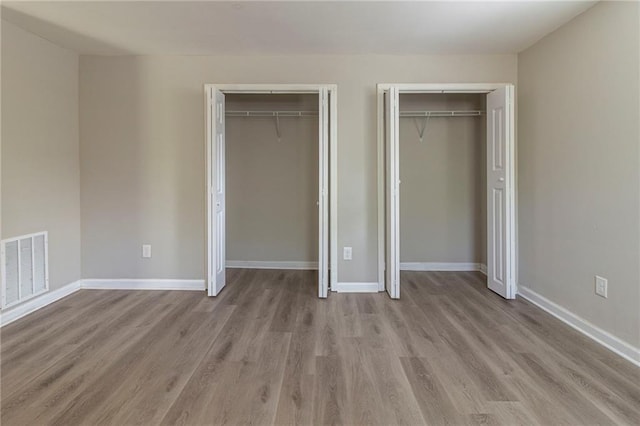 3821 Paul Samuel Rd NW, Kennesaw, GA 30152 - unfurnished bedroom featuring two closets, wood finished floors, baseboards, and visible vents