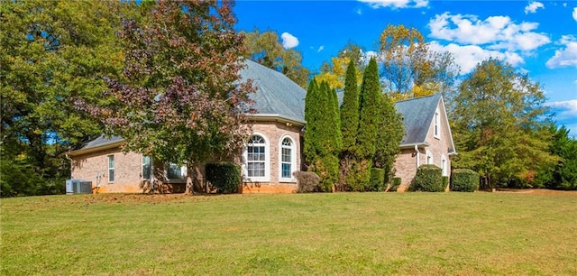 view of front of home with cooling unit and a front yard