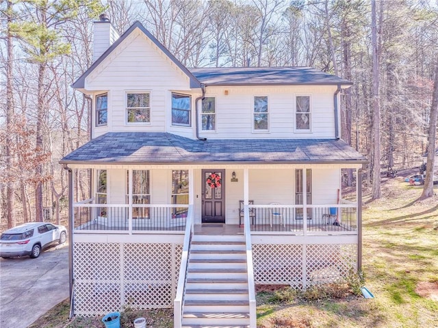 view of front of house with driveway, stairs, a chimney, and a porch
