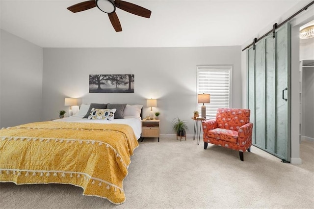 bedroom with a barn door, ceiling fan, and carpet floors