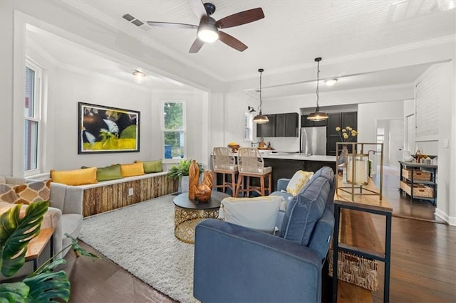 living room with dark hardwood / wood-style flooring, ceiling fan, and crown molding