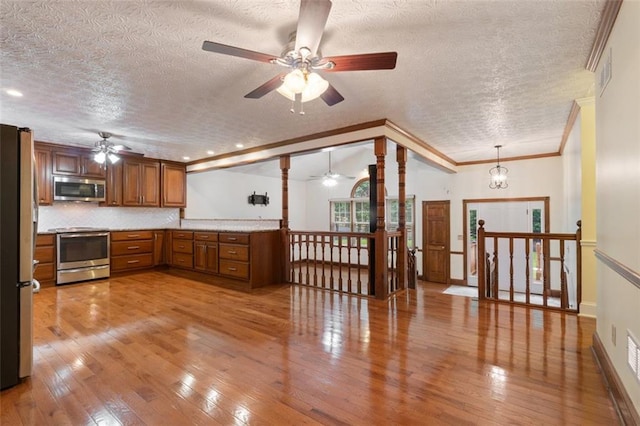 48 Saddle Field Cir NW, Cartersville, GA 30121 - kitchen with appliances with stainless steel finishes, a ceiling fan, a textured ceiling, ornamental molding, and brown cabinetry