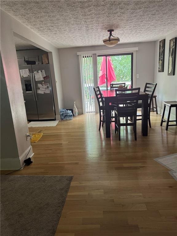 dining area with a textured ceiling and wood finished floors