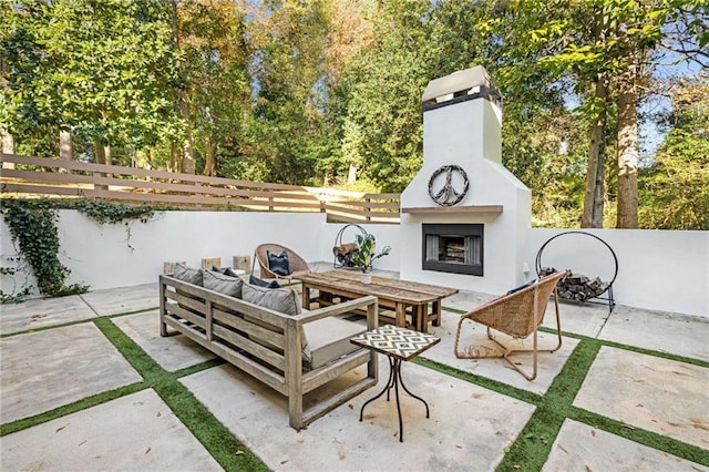 view of patio featuring an outdoor living space with a fireplace and fence