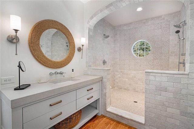 bathroom featuring wood finished floors, walk in shower, and vanity