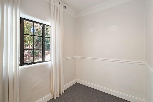 unfurnished room with ornamental molding, dark carpet, and baseboards