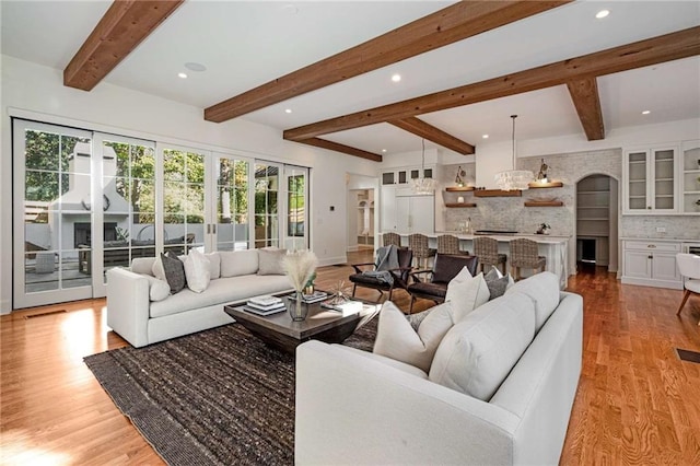 living room with french doors, light wood finished floors, recessed lighting, visible vents, and beamed ceiling