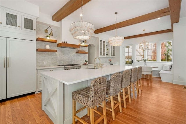 kitchen featuring glass insert cabinets, light countertops, a notable chandelier, and open shelves