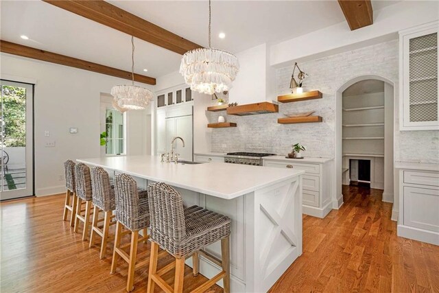 kitchen with an island with sink, sink, a breakfast bar area, and a notable chandelier