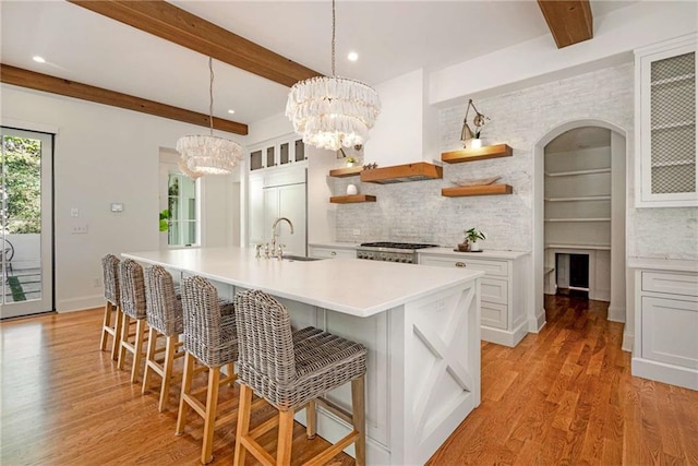 kitchen featuring a breakfast bar, white cabinetry, stove, paneled fridge, and decorative light fixtures