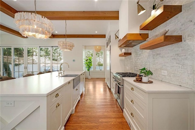 kitchen featuring premium appliances, decorative light fixtures, light countertops, open shelves, and a sink