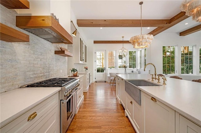 kitchen with light countertops, high end stainless steel range oven, a sink, and decorative light fixtures