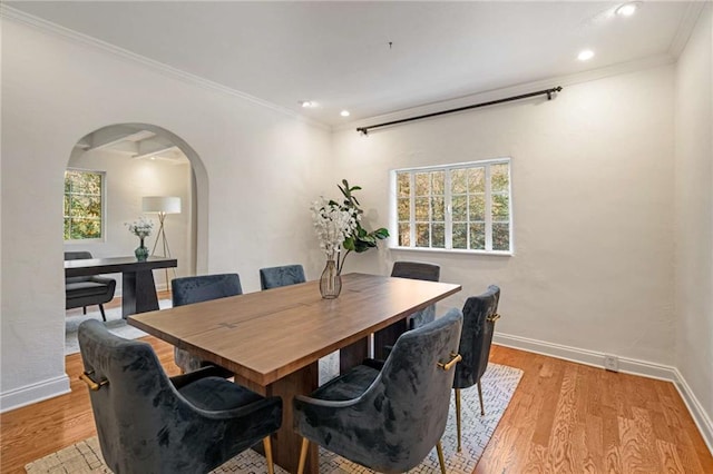 dining area with light wood-type flooring, arched walkways, and baseboards