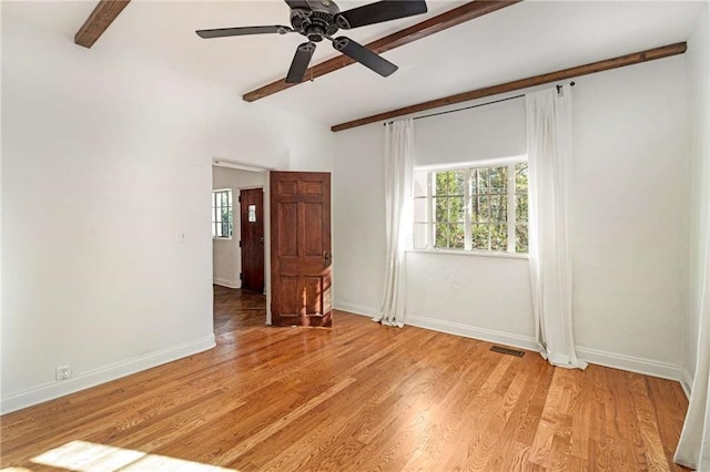 spare room featuring light wood-type flooring, visible vents, beamed ceiling, and baseboards