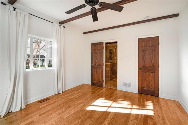 unfurnished bedroom with baseboards, beamed ceiling, visible vents, and light wood-style floors