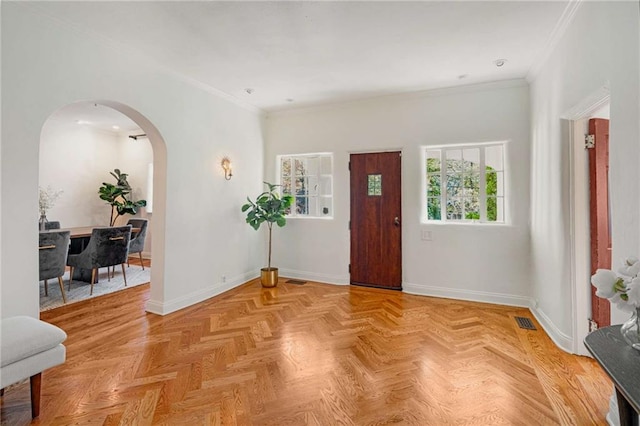 entryway with visible vents, crown molding, arched walkways, and baseboards