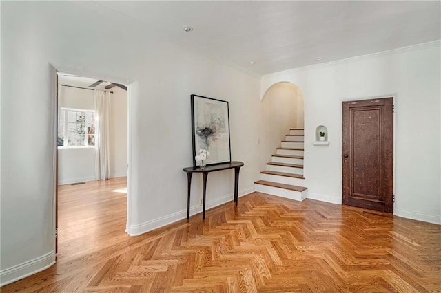 entrance foyer featuring baseboards, arched walkways, and crown molding