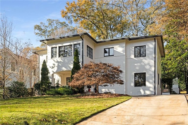 view of front of property featuring a front yard, driveway, and stucco siding