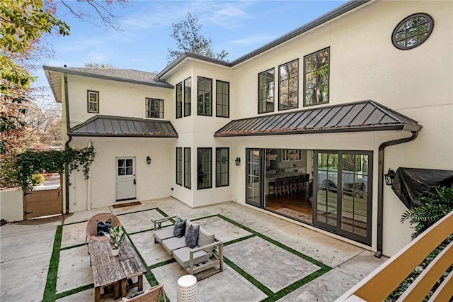 rear view of property featuring a standing seam roof, a patio, metal roof, and stucco siding