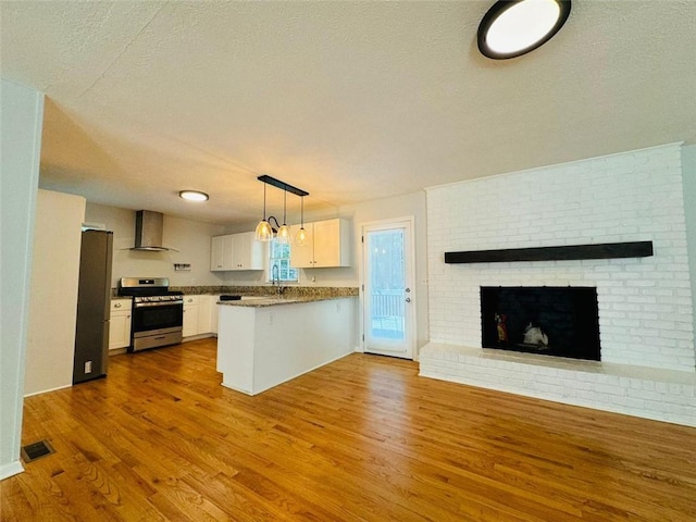 3210 Ebenezer Rd, Marietta, GA 30066 - kitchen with appliances with stainless steel finishes, wall chimney range hood, open floor plan, a textured ceiling, and a peninsula
