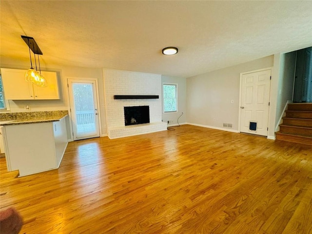 3210 Ebenezer Rd, Marietta, GA 30066 - unfurnished living room featuring light wood-style flooring, a brick fireplace, stairs, and baseboards