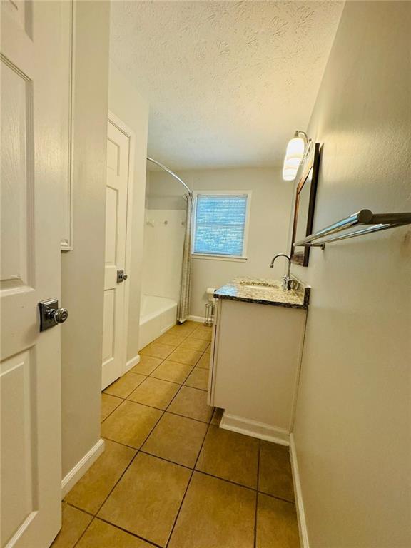 3210 Ebenezer Rd, Marietta, GA 30066 - full bath with vanity, tile patterned floors, a textured ceiling, shower / bathtub combination with curtain, and baseboards