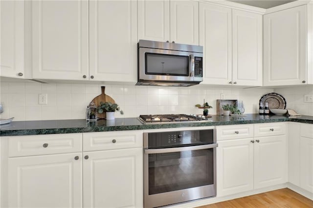 4963 Kingsbridge Ct, Powder Springs, GA 30127 - kitchen with appliances with stainless steel finishes, white cabinets, decorative backsplash, and dark stone counters