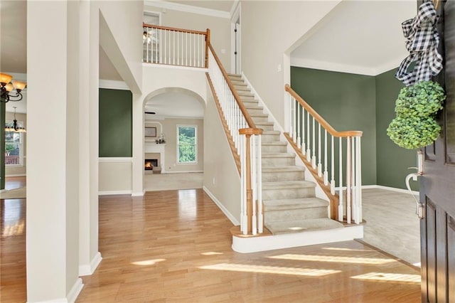 4963 Kingsbridge Ct, Powder Springs, GA 30127 - foyer with arched walkways, wood finished floors, a warm lit fireplace, stairway, and baseboards
