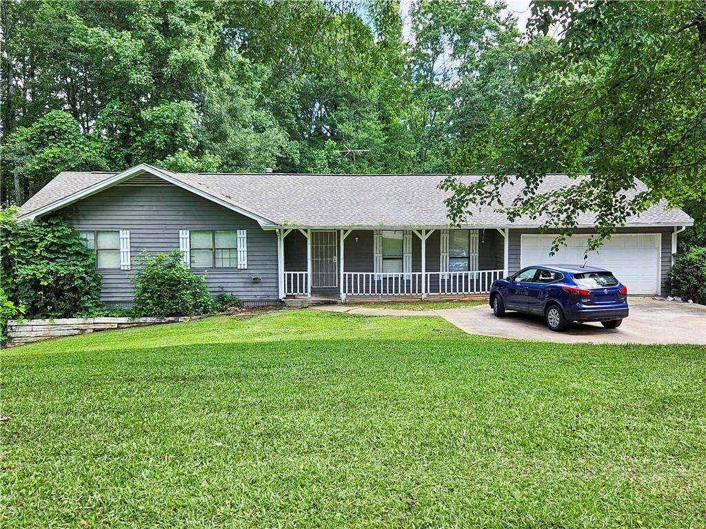 195 Lakeside Dr, Ellenwood, GA 30294 - single story home with covered porch, concrete driveway, an attached garage, a front lawn, and roof with shingles