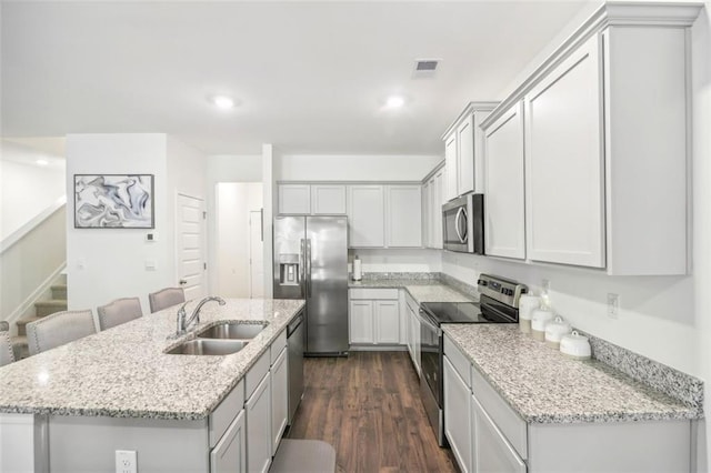 kitchen featuring a center island with sink, visible vents, dark wood-style floors, appliances with stainless steel finishes, and a sink