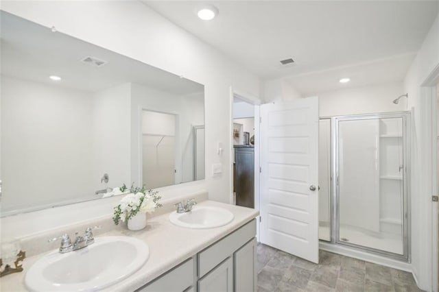 bathroom featuring double vanity, a stall shower, and a sink