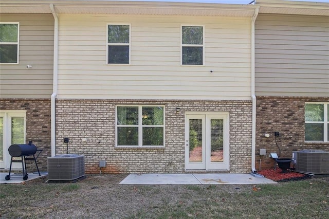 back of property featuring central air condition unit, a patio area, a yard, and brick siding