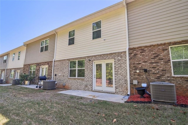 back of property with a yard, brick siding, a patio, and cooling unit