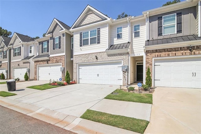 townhome / multi-family property with a standing seam roof, brick siding, driveway, and metal roof