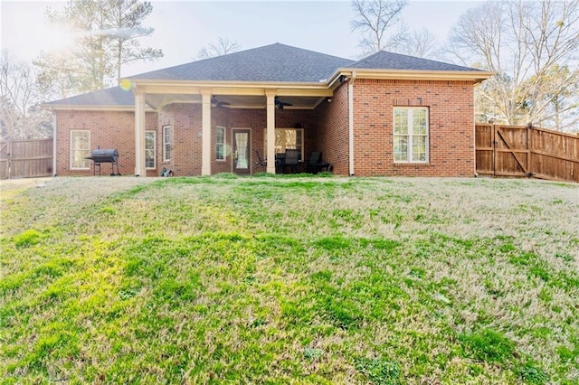 back of house with ceiling fan, a yard, brick siding, and a fenced backyard