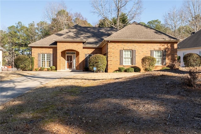 view of front of house featuring brick siding and roof with shingles