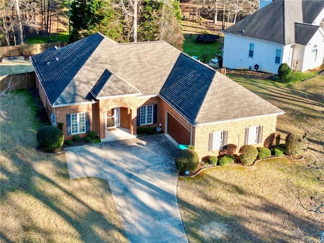 view of front facade with a shingled roof, fence, concrete driveway, and brick siding