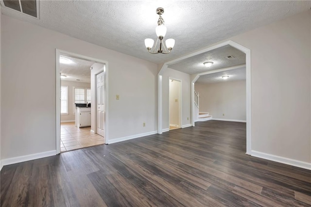 unfurnished dining area featuring an inviting chandelier, a textured ceiling, and dark hardwood / wood-style floors