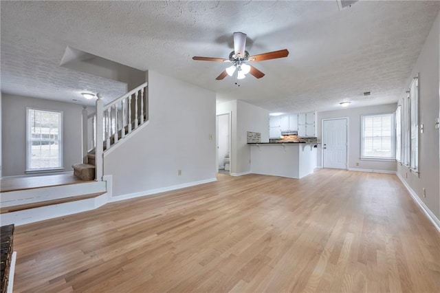 unfurnished living room with light wood-type flooring, a textured ceiling, and ceiling fan