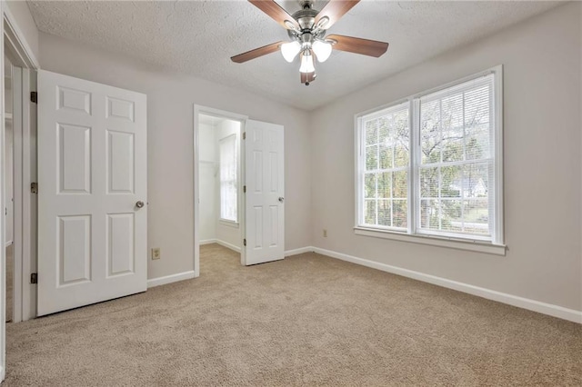 unfurnished bedroom with ceiling fan, light carpet, and a spacious closet