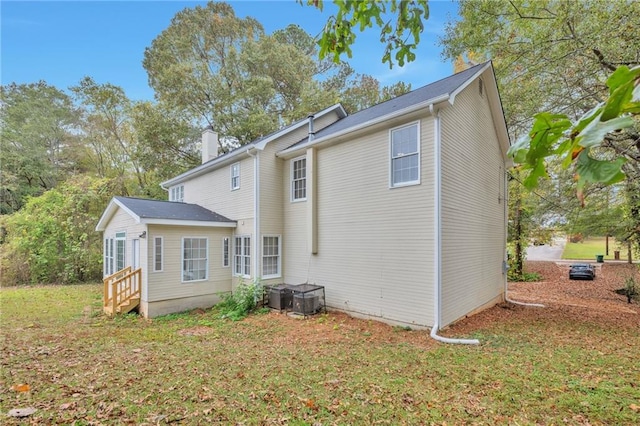 rear view of property with a lawn and cooling unit