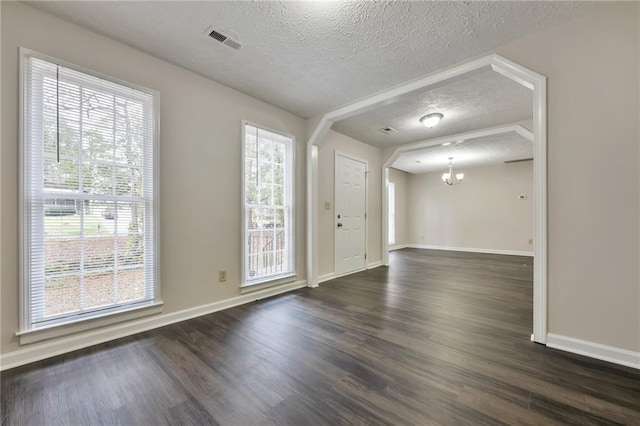 entryway with a wealth of natural light, a textured ceiling, and dark hardwood / wood-style flooring