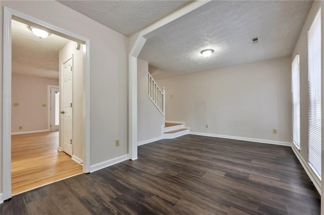 spare room with a textured ceiling and dark hardwood / wood-style floors