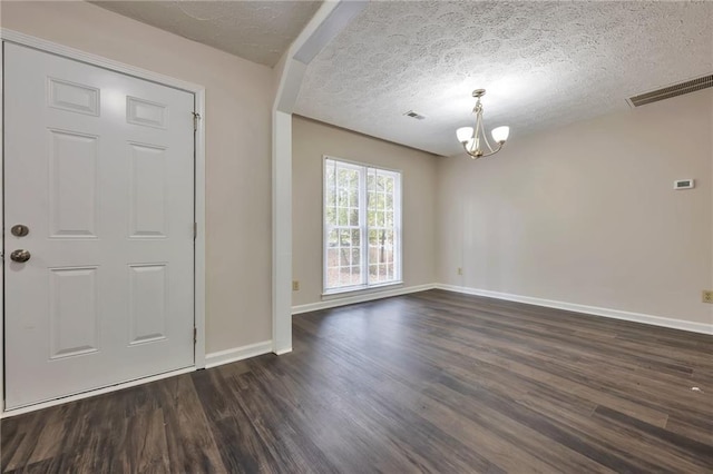 entryway with dark hardwood / wood-style floors, a textured ceiling, and an inviting chandelier