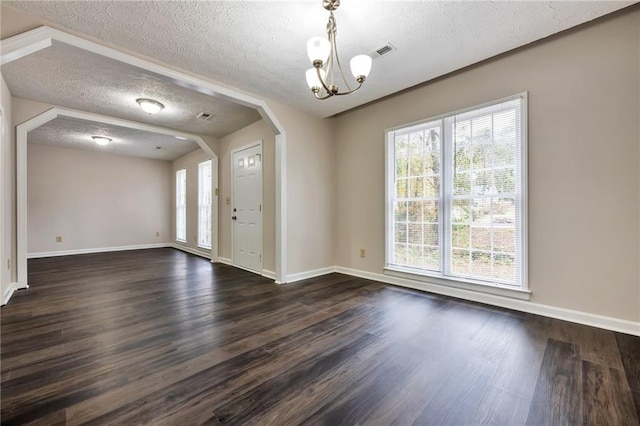 entrance foyer featuring a textured ceiling, a notable chandelier, and dark hardwood / wood-style floors