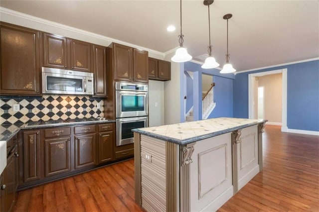 kitchen with ornamental molding, dark hardwood / wood-style flooring, a kitchen island, pendant lighting, and stainless steel appliances