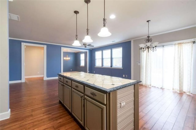 kitchen with an inviting chandelier, crown molding, hanging light fixtures, dark hardwood / wood-style flooring, and a kitchen island